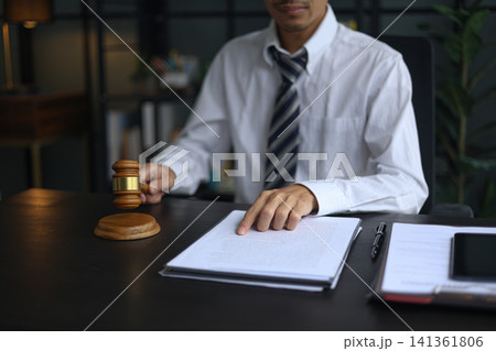Lawyer Reviewing Contract and Documents with Gavel on Desk. 141361806