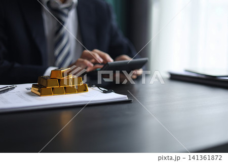 Gold investment Concept. Businessman working on financial planning and gold investment analysis with bullion and calculator. 141361872