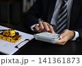 Gold volatility. Businessman calculating profit from fine gold bar investments. 141361873