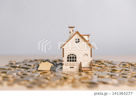 Wooden house with home keys surrounded by scattered coins, symbolizing property ownership, mortgage payment, real estate purchase, home investment, and financial security. Wooden house with home keys surrounded by scattered coins, symbolizing property ownership, mortgage payment, real estate purchase, home investment, and financial security. 141363277
