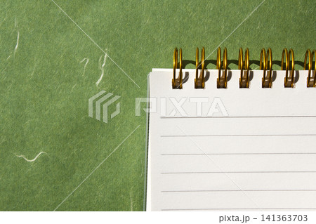 It is a small notebook placed on a green background. It is a small notebook placed on a green background. 141363703