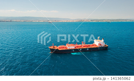 Aerial view of LPG tanker ship sailing near Mediterranean coastline with city skyline in background Aerial view of LPG tanker ship sailing near Mediterranean coastline with city skyline in background 141365062