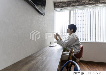 休憩室でスマホを操作する若い作業員 141365358