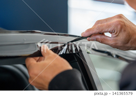 A car wrapping specialist applies a polyurethane film to the car. Detailer PPF 141365579