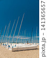 Small sailboats stored on a sandy beach in Spain with tall masts reaching into a clear blue sky. 141365657