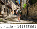 Young backpacker walking through historic stone street in Rupit village, Catalonia, Spain, exploring medieval architecture 141365661