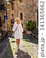 Young woman walking through narrow cobblestone street in historic stone village, exploring authentic rural Catalonia 141365662