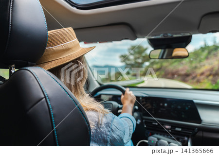 Woman driving car on winding mountain route viewed from passenger perspective Woman driving car on winding mountain route viewed from passenger perspective 141365666