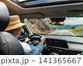 Woman driving car on scenic mountain highway viewed from back seat 141365667