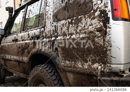 Dirty vehicle with mud splatters on body, windows, wheels, tires. Dirty offroad suv car covered in dirt. Rugged terrain adventure, extreme driving, four wheel drive challenges Dirty vehicle with mud splatters on body, windows, wheels, tires. Dirty offroad suv car covered in dirt. Rugged terrain adventure, extreme driving, four wheel drive challenges 141366086