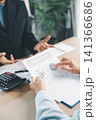 Business people reviewing financial report with charts and calculator during office meeting, representing accounting consultation, sales analysis and corporate planning. 141366686