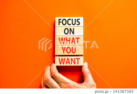 Focus on what you want symbol. Concept words Focus on what you want on beautiful wooden blocks. Beautiful orange background. Psychologist hand. Psychological focus on what you want concept. Copy space 141367385