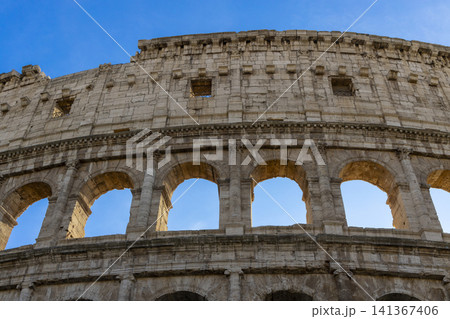Famous Coliseum in Rome. Colosseum, or Coliseum. Part of the wall of an antique stone structure with arches. Italy, Europe. Famous touristic place in the world, Europe. Beautiful blue sky background. Famous Coliseum in Rome. Colosseum, or Coliseum. Part of the wall of an antique stone structure with arches. Italy, Europe. Famous touristic place in the world, Europe. Beautiful blue sky background. 141367406