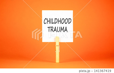Childhood trauma words symbol. Concept words Childhood trauma on beautiful white paper on wooden clothespin. Beautiful orange background. Psychological childhood trauma support concept. Copy space. 141367419