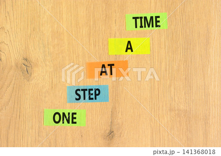 One step at a time symbol. Concept words One step at a time on beautiful colored papers. Beautiful wooden background. Business and one step at a time concept. Copy space. One step at a time symbol. Concept words One step at a time on beautiful colored papers. Beautiful wooden background. Business and one step at a time concept. Copy space. 141368018