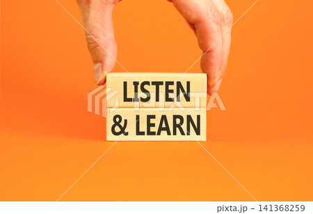 Listen and learn words symbol. Concept words Listen and learn on beautiful wooden blocks. Beautiful orange background. Businessman hand. Business listen and learn support concept. Copy space. 141368259