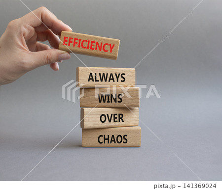 Efficiency symbol. Wooden blocks with words Efficiency Always Wins Over Chaos. Businessman hand. Beautiful grey background. Businessman hand. Business and Efficiency concept. Copy space Efficiency symbol. Wooden blocks with words Efficiency Always Wins Over Chaos. Businessman hand. Beautiful grey background. Businessman hand. Business and Efficiency concept. Copy space 141369024