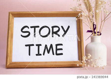 Story Time symbol. Concept words Story Time on beautiful wooden picture frame. Beautiful pink background with flower vase. Business and Story Time concept. Copy space. 141369044