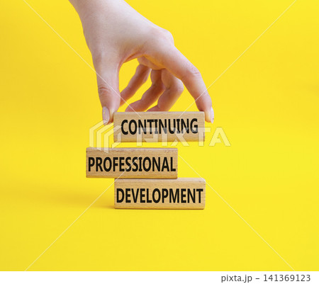 Continuing Development symbol. Concept words Continuing Professional Development on wooden blocks. Businessman hand. Beautiful yellow background. Business and Development concept. Copy space Continuing Development symbol. Concept words Continuing Professional Development on wooden blocks. Businessman hand. Beautiful yellow background. Business and Development concept. Copy space 141369123
