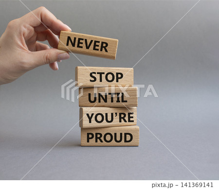 Never Stop symbol. Wooden blocks with words Never Stop Until You are Proud. Businessman hand. Beautiful grey background. Business and Never Stop concept. Copy space Never Stop symbol. Wooden blocks with words Never Stop Until You are Proud. Businessman hand. Beautiful grey background. Business and Never Stop concept. Copy space 141369141