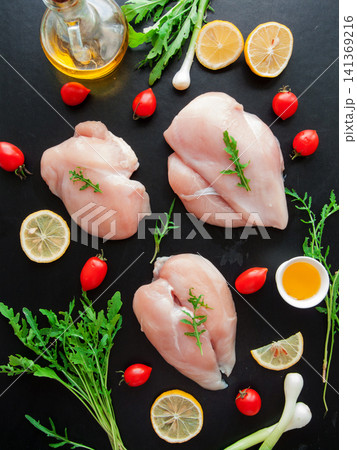 Fresh raw chicken breast meat with greens, fresh cherry tomatoes and lemon slices preparing to cook 141369216