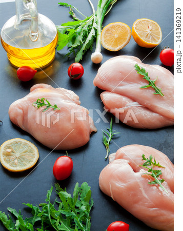 Fresh raw chicken breast meat with greens, fresh cherry tomatoes and lemon slices preparing to cook Fresh raw chicken breast meat with greens, fresh cherry tomatoes and lemon slices preparing to cook 141369219