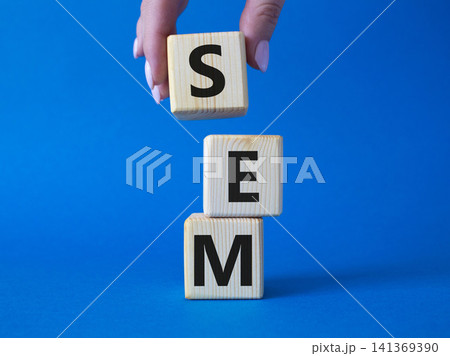 SEM - Search Engine Marketing symbol. Wooden cubes with words SEM. Businessman hand. Beautiful blue background. Business and SEM concept. Copy space. SEM - Search Engine Marketing symbol. Wooden cubes with words SEM. Businessman hand. Beautiful blue background. Business and SEM concept. Copy space. 141369390