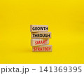 Smart strategy symbol. Wooden blocks with words Growth through smart strategy. Beautiful yellow background. Business and Smart strategy concept. Copy space 141369395