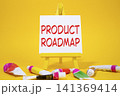 Product Roadmap symbol. Concept word Product Roadmap on wooden blocks. Beautiful yellow background with paints and easel. Business and Product Roadmap concept. Copy space 141369414