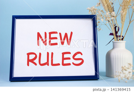 New rules symbol. Concept words New rules on beautiful wooden picture frame. Beautiful light blue background with flower vase. Business and New rules concept. Copy space. New rules symbol. Concept words New rules on beautiful wooden picture frame. Beautiful light blue background with flower vase. Business and New rules concept. Copy space. 141369415