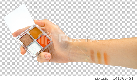 Hand holding a small four-color eyeshadow palette with orange, brown, and glitter shades. Makeup swatches applied to the forearm. Professional beauty product photography isolated. Hand holding a small four-color eyeshadow palette with orange, brown, and glitter shades. Makeup swatches applied to the forearm. Professional beauty product photography isolated. 141369451