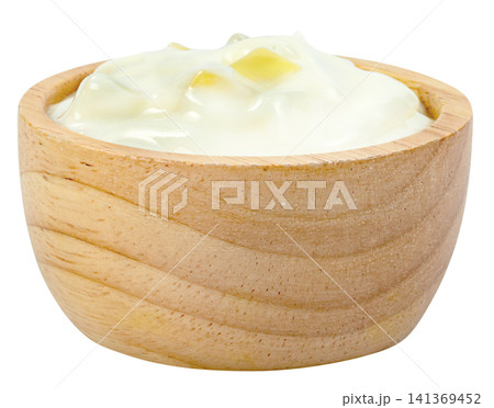 Creamy white yogurt with yellow fruit chunks served in a small round wooden bowl isolated. Healthy dairy product, breakfast snack, or cooking ingredient concept. Creamy white yogurt with yellow fruit chunks served in a small round wooden bowl isolated. Healthy dairy product, breakfast snack, or cooking ingredient concept. 141369452