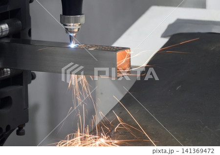 High-power fiber laser cut machine operation cutting a steel square pipe with a dramatic fire splash. 141369472