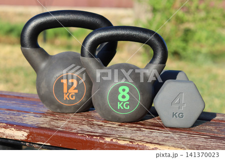 old dumbbell on wooden bench 141370023