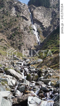 Dramatic mountain landscape with a tall waterfall cascading down a steep rocky cliff face, power concept. Dramatic mountain landscape with a tall waterfall cascading down a steep rocky cliff face, power concept. 141370164