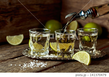 Tequila with salt and lime slices on a silver tray. Tequila with salt and lime slices on a silver tray. 141370479