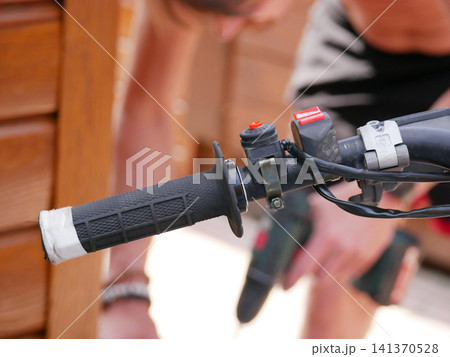 Man repairing motorcycle handlebar. Mechanic holding tools for maintenance of dirt bike steering control. Engineering service and mechanical fix of vehicle system in workshop garage. Man repairing motorcycle handlebar. Mechanic holding tools for maintenance of dirt bike steering control. Engineering service and mechanical fix of vehicle system in workshop garage. 141370528