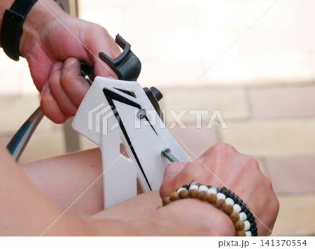 Man assembling white plastic equipment with metal screw. Hands of a handyman working on repair or construction project. DIY home improvement task using simple tool for maintenance. Man assembling white plastic equipment with metal screw. Hands of a handyman working on repair or construction project. DIY home improvement task using simple tool for maintenance. 141370554