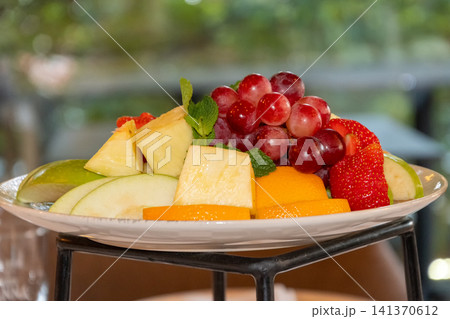 Fresh mixed fruit platter with grapes pineapple apples strawberries oranges and mint served for healthy restaurant breakfast buffet Fresh mixed fruit platter with grapes pineapple apples strawberries oranges and mint served for healthy restaurant breakfast buffet 141370612