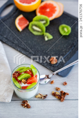 creamy yogurt with kiwi grapefruit and walnut topping closeup 141370756