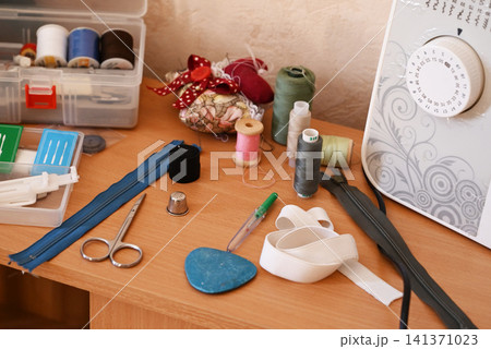 Sewing tools and materials on a desk near a sewing machine in a workspace 141371023
