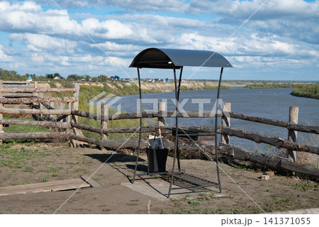 Riverside shelter with a water fountain in a rural area near the riverbank on a sunny day Riverside shelter with a water fountain in a rural area near the riverbank on a sunny day 141371055