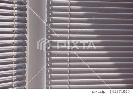 Modern window blinds on two glass panes creating geometric shadow pattern Modern window blinds on two glass panes creating geometric shadow pattern 141371090