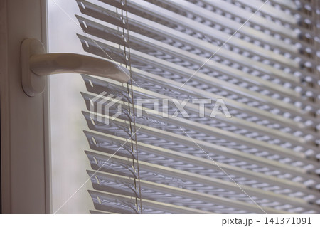 White plastic window frame with handle and modern horizontal blinds 141371091
