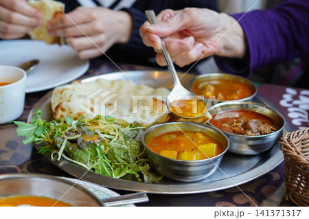 レストランで孫と一緒にインドカレーとナンを食べるシニアの祖母の手元 レストランで孫と一緒にインドカレーとナンを食べるシニアの祖母の手元 141371317