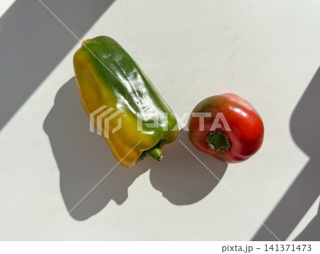 Fresh bell peppers on white surface in natural sunlight creating bold shadows and minimal food composition. Healthy nutrition, cooking, vegetarian lifestyle, fresh produce, wellness, meal preparation, Fresh bell peppers on white surface in natural sunlight creating bold shadows and minimal food composition. Healthy nutrition, cooking, vegetarian lifestyle, fresh produce, wellness, meal preparation, 141371473