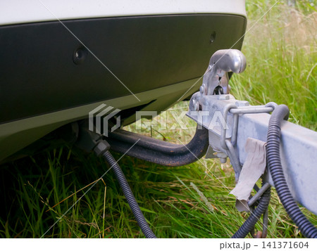 Trailer tow hitch attached to vehicle bumper. Metal coupling mechanism connected to car for towing. Heavy equipment transport and road travel safety. Automotive connection and gear. Trailer tow hitch attached to vehicle bumper. Metal coupling mechanism connected to car for towing. Heavy equipment transport and road travel safety. Automotive connection and gear. 141371604