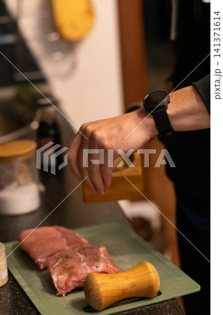 Cook Sprinkling Salt and Pepper on Raw Pork Ribs Board Cook Sprinkling Salt and Pepper on Raw Pork Ribs Board 141371614