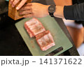 Chef Holding Wooden Mortar Over Seasoned Pork on Board 141371622