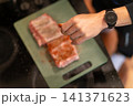 Overhead View Applying Red Spice Rub on Raw Pork Ribs 141371623